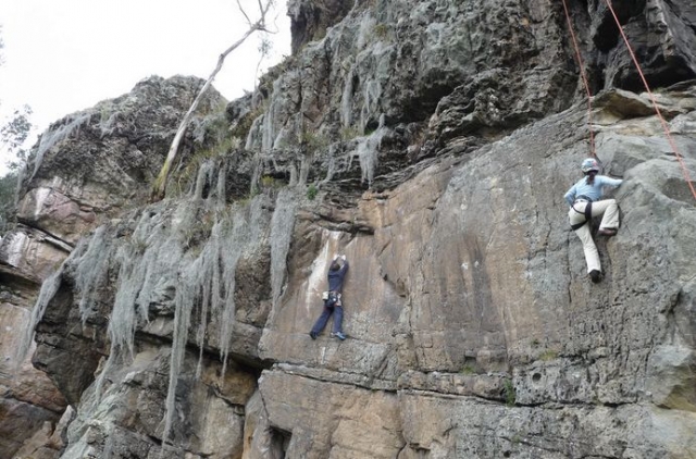 dos chicos escalando una roca natural